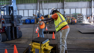 Dos montadores de maquinaria bajando maquinaria industrial para su instalación