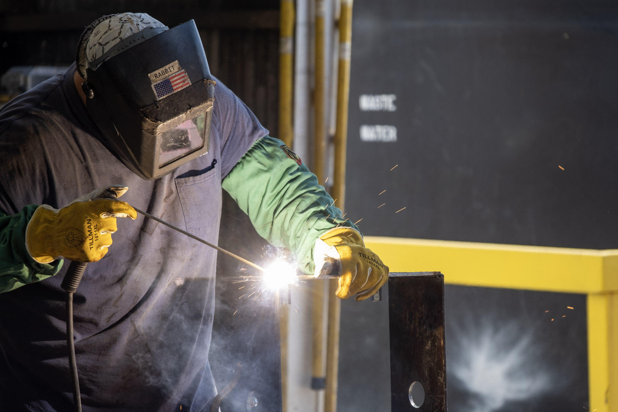 Nabholz employee wearing welding mask and safety gear welding metal parts together